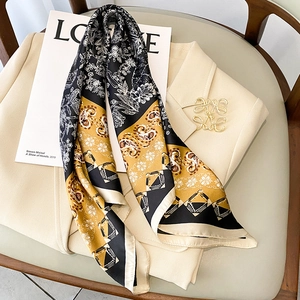 Detail of silk scarf with floral paisley prints styled on a beige suit and magazine