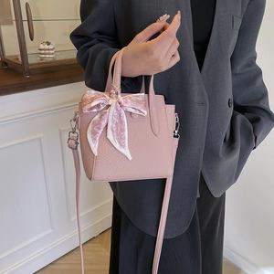 Sac seau rose à texture litchi avec foulard en soie, porté par un mannequin