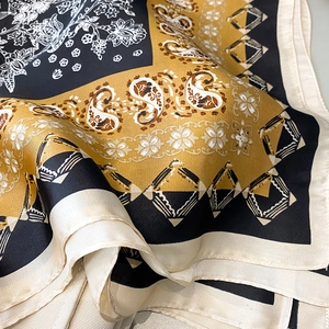 Close-up of elegant paisley print silk scarf with luxury golden and black patterns