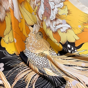 Dettaglio di un foulard in seta di lusso con carpa koi dorata e stampa floreale