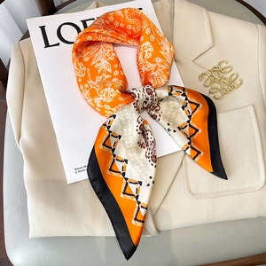 Elegant 70x70 orange floral silk scarf tied on a beige blazer with retro patterns