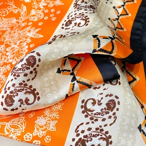 Detailed view of paisley silk scarf with vibrant orange geometric patterns and floral motifs