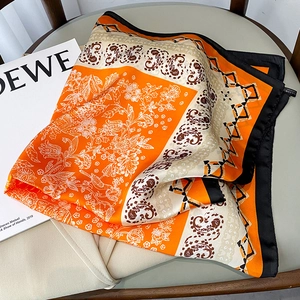 Detail of 70x70 silk-feel square scarf with paisley floral prints and orange satin finish