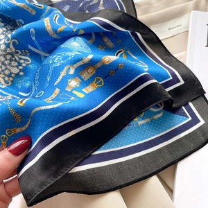 Détail rapproché d'un foulard en soie bleue avec motifs vintage de chaînes et montres