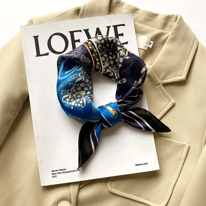 Vue détaillée d'un foulard en soie à motifs floraux posé sur un blazer beige chic