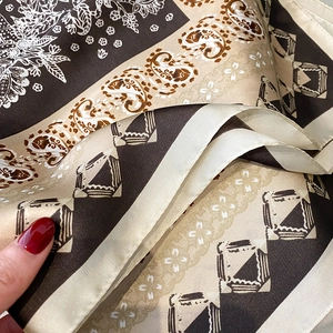 Close-up of printed silk-like square scarf featuring paisley and floral patterns