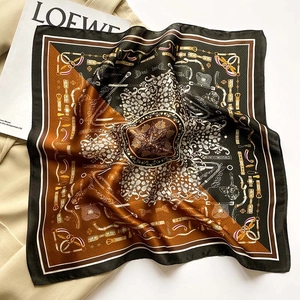 Détails d'un foulard en soie vintage aux motifs de chaînes sur un manteau beige