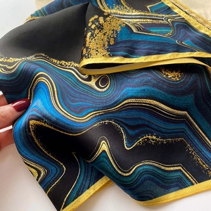Detailed close-up of dark blue marble print silk scarf with luxury golden edges