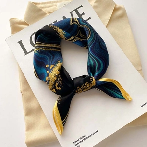 Detail of silk scarf with abstract marble pattern and gold dust texture in elegant knot