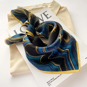 Detailed view of vintage marble print silk scarf with yellow edges on beige shirt