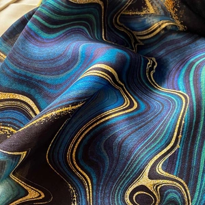 Detail of silk scarf showing marble patterns with golden glitter lines and satin texture