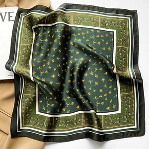 Detail of dark green floral silk scarf with yellow blossoms on a khaki coat