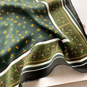Detail of green floral silk scarf with smooth satin texture and elegant pleated folds