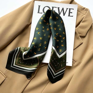 Close-up of vintage floral silk scarf with geometric borders on a tan blazer