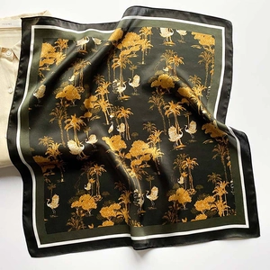 Close-up of vintage silk scarf featuring gold crane and palm tree prints on dark green