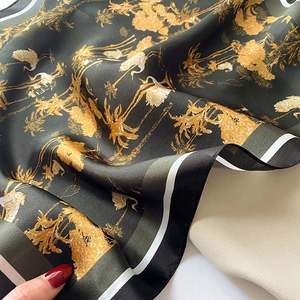 Detail of silk-like scarf featuring vintage crane and tropical palm tree prints with green borders