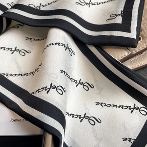 Nahaufnahme eines Seidenschals mit schwarzen Buchstaben und elegantem Monochrom-Rand