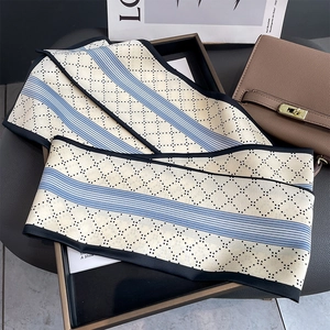 Eleganter cremefarbener schmaler Seidenschal mit geometrischem Muster auf Ledertasche