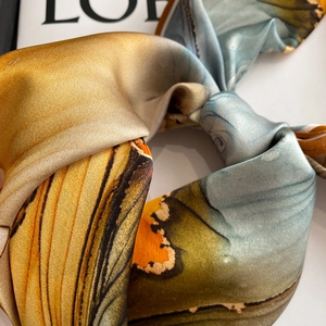 Gros plan détaillé d'un foulard en soie noué aux motifs abstraits et bords contrastés