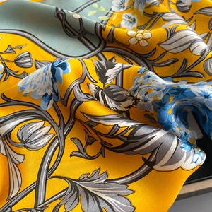 Detailed close-up of retro floral print silk scarf with glossy yellow fabric texture