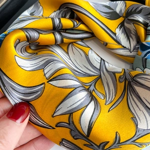 Close-up of yellow silk scarf with grey and white leaf patterns and smooth texture