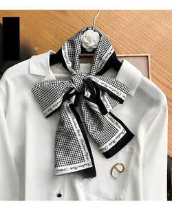 Detail of classic houndstooth silk scarf tied on a shirt with a white camellia accessory