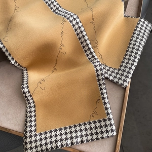 Macro detail of houndstooth edge and letter print on yellow silk skinny scarf