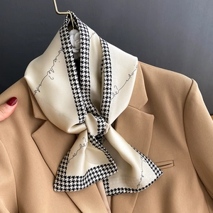 Beige silk scarf with houndstooth edge and elegant script tied on a camel blazer