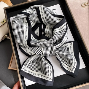 Classic houndstooth silk scarf with letter border displayed in an elegant tray