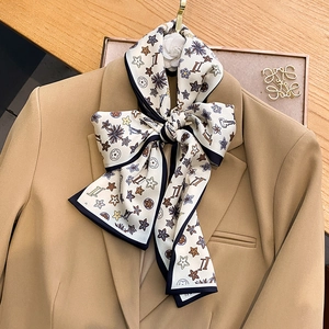 Detail of silk-like scarf tied in a bow on a blazer lapel featuring floral patterns