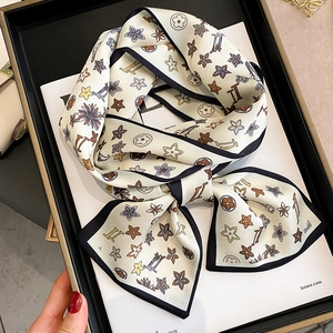 Detailed close-up of a cream-colored silk scarf featuring elegant floral and star patterns