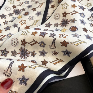 Detailed close-up of cream floral silk scarf with retro key prints and black borders