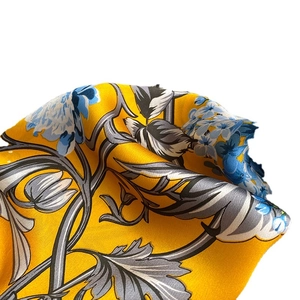 Elegant floral silk scarf in yellow and blue with soft satin finish on white background