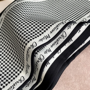 Detailed view of houndstooth silk scarf with elegant black border and cursive typography
