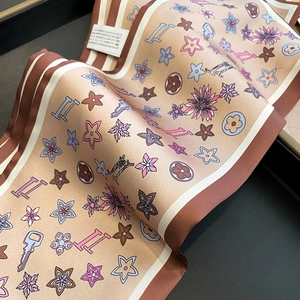 Detail of silk texture scarf with champagne floral print and striped edge on a dark box