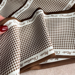 Detailed view of soft houndstooth pattern fabric with elegant cursive lettering trim