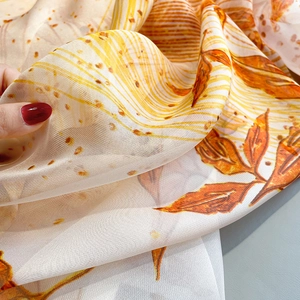 Close-up of lightweight semi-transparent scarf with vibrant orange maple leaf print