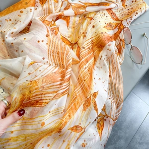 Detailed macro view of an orange autumn leaf pattern on a soft long silk scarf