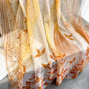 Detail showing sheer floral chiffon scarf with artistic orange leaf print and soft texture
