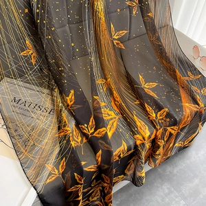 Detail of elegant black and orange leaf pattern silk scarf draped on a chair