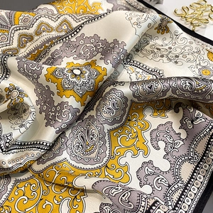 Nahaufnahme eines Seidenschals mit Paisley-Muster in Gold und eleganter Textur
