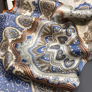 Nahaufnahme eines Seidenschals mit Paisley-Muster und elegantem Fall in Blau und Beige