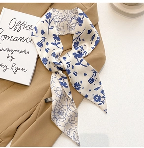 Détail d'un foulard en soie blanche à motifs floraux sur une veste de couleur kaki