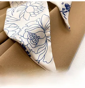 Détail d'un foulard en soie avec motif floral bleu sur tissu en satin blanc cassé