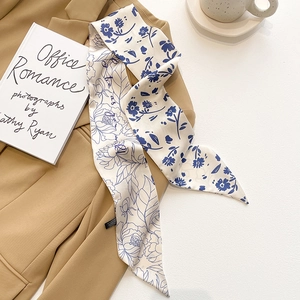 Détail d'un foulard twilly en soie à fleurs sur un blazer kaki avec fond artistique