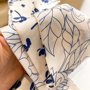 Vue détaillée d'un foulard en soie imprimé montrant la texture lisse et le motif floral