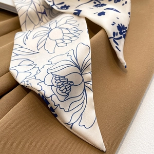 Gros plan d'un foulard en soie à fleurs bleu foncé sur un tissu satiné crème élégant