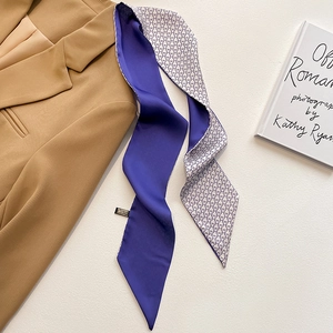 Détail d'un foulard en soie avec motif géométrique violet et M sur un blazer chic