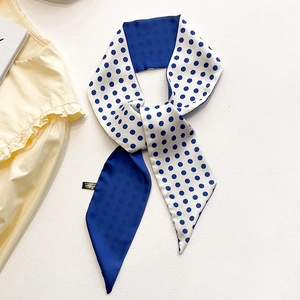 Gros plan d'un foulard en soie à pois bleus et blancs sur un chemisier à volants