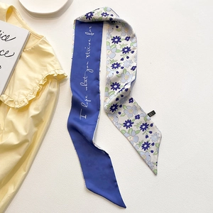 Détail d'un foulard étroit double face avec motif floral et texte artistique